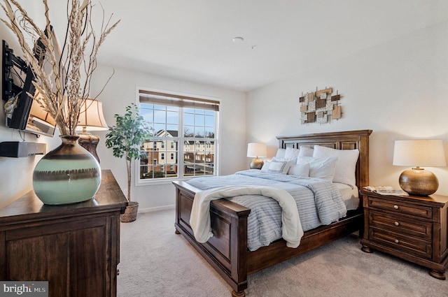 bedroom with light colored carpet and baseboards