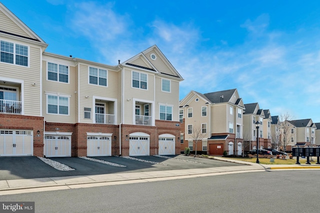 view of front facade with brick siding, a residential view, driveway, and an attached garage