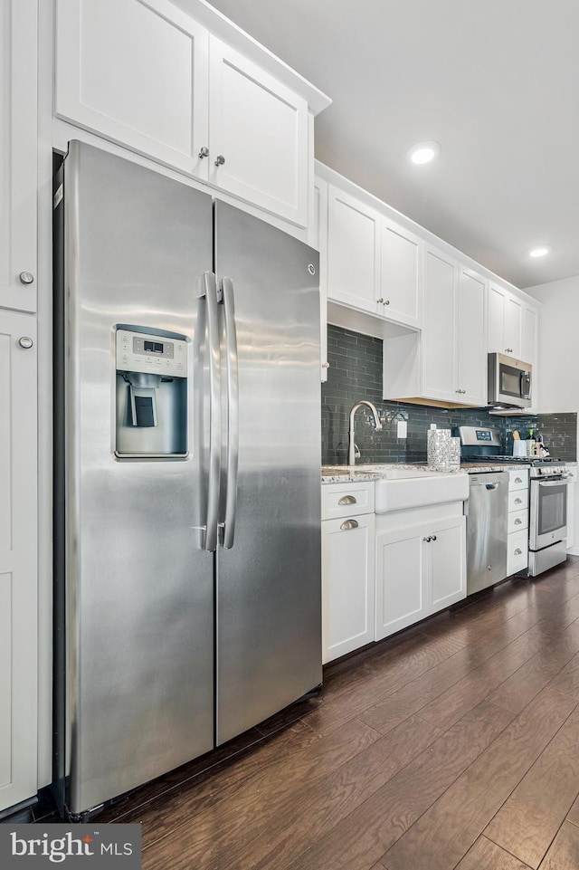 kitchen featuring dark wood finished floors, white cabinets, backsplash, and appliances with stainless steel finishes