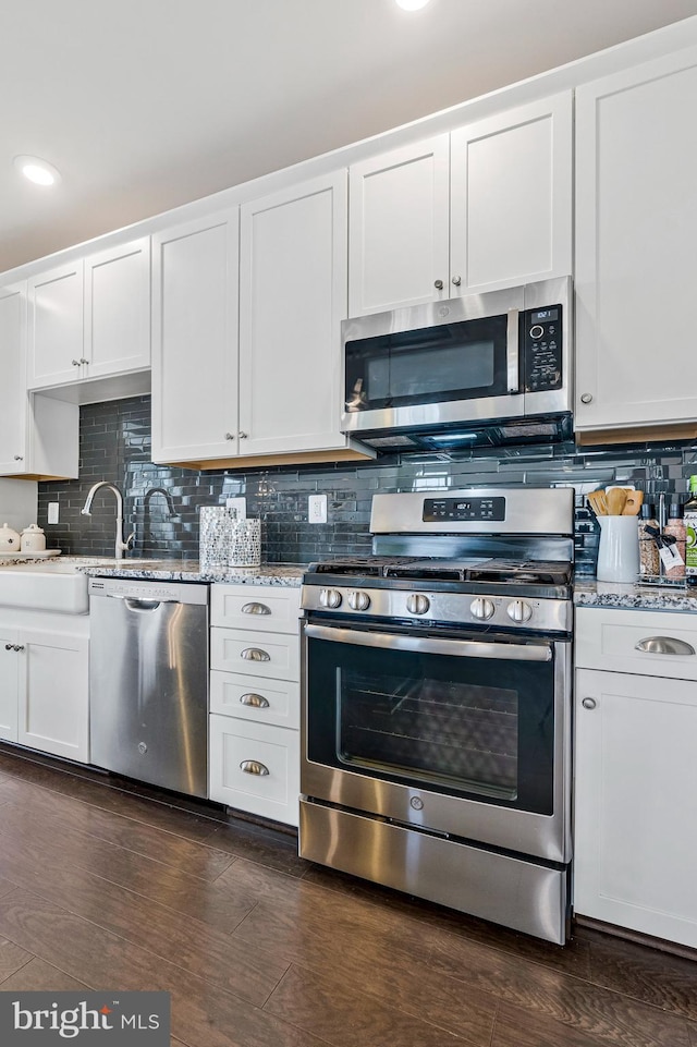 kitchen with light stone counters, dark wood finished floors, and appliances with stainless steel finishes