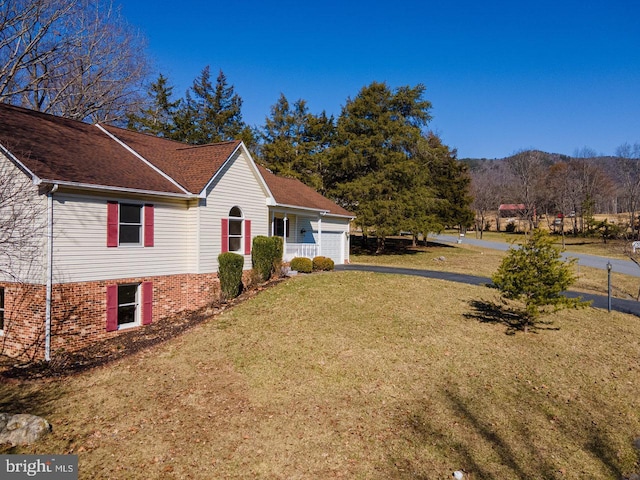 view of side of property with a garage, a yard, and driveway