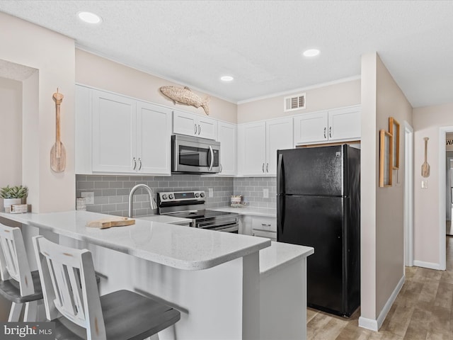 kitchen featuring visible vents, stainless steel appliances, backsplash, and a peninsula