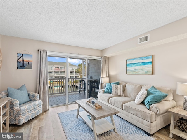 living area featuring visible vents, wood finished floors, and a textured ceiling