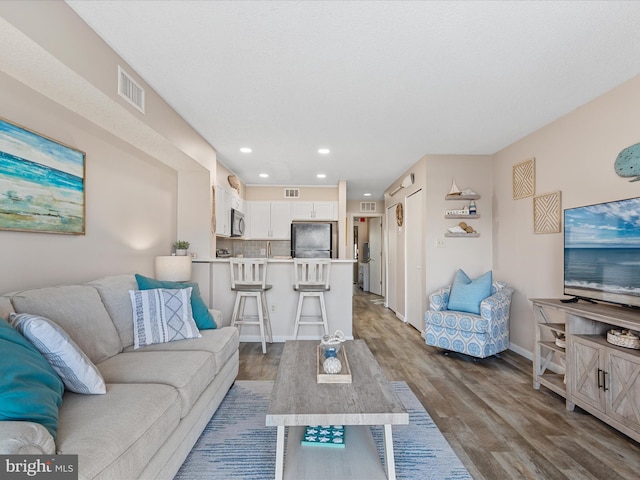 living area featuring dark wood-style flooring, recessed lighting, baseboards, and visible vents