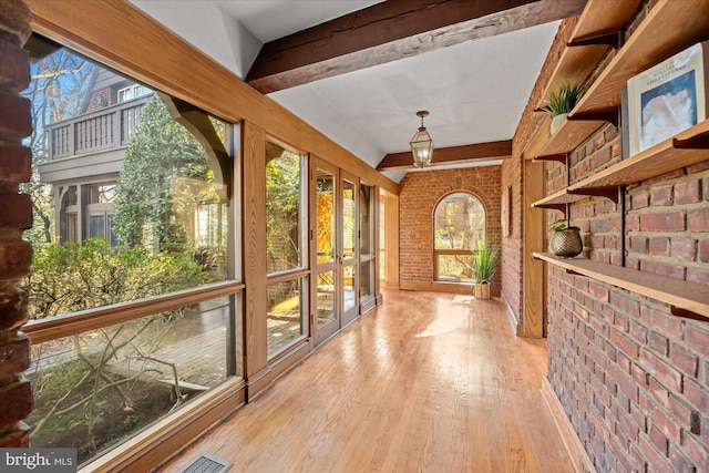 unfurnished sunroom featuring beam ceiling, plenty of natural light, and visible vents