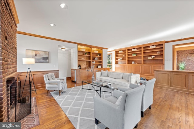 living room featuring recessed lighting, a brick fireplace, light wood-type flooring, and crown molding