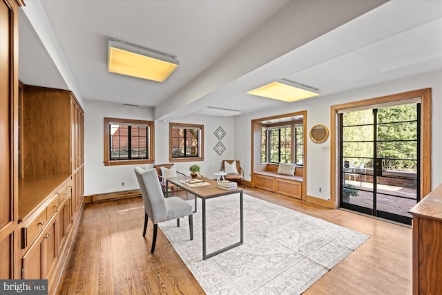 office space featuring light wood finished floors, a baseboard heating unit, and baseboards