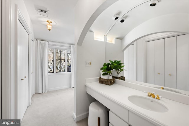 bathroom featuring visible vents, baseboards, and vanity