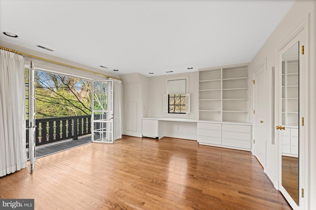 unfurnished room with recessed lighting, visible vents, wood finished floors, and built in desk