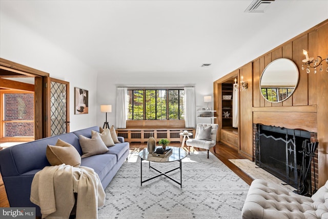 living area with a premium fireplace, visible vents, wood finished floors, and radiator heating unit