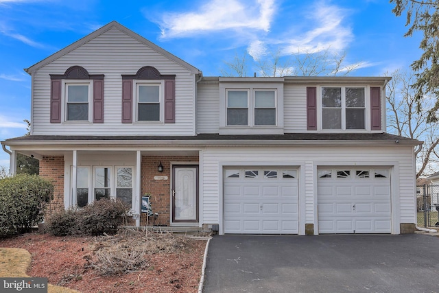 traditional home featuring aphalt driveway, brick siding, and a garage