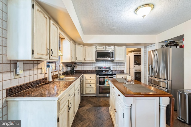 kitchen with butcher block countertops, a sink, backsplash, appliances with stainless steel finishes, and stacked washer / drying machine