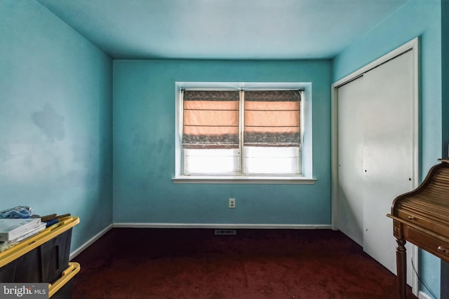 bedroom featuring baseboards, dark colored carpet, and a closet