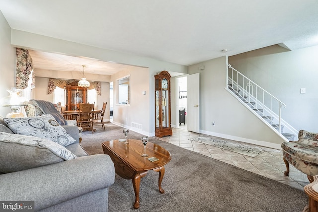 living room featuring stairway, baseboards, visible vents, carpet floors, and tile patterned flooring