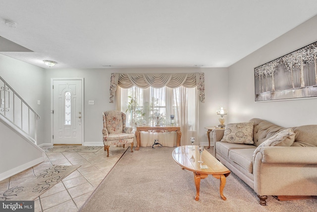 living area featuring tile patterned flooring, stairs, and baseboards