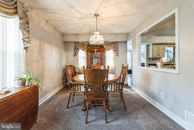 dining room with dark colored carpet, visible vents, baseboards, and a chandelier