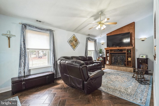 living room with a wealth of natural light, visible vents, a tile fireplace, and vaulted ceiling