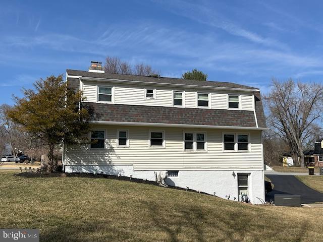 view of home's exterior with a lawn, a chimney, and a shingled roof