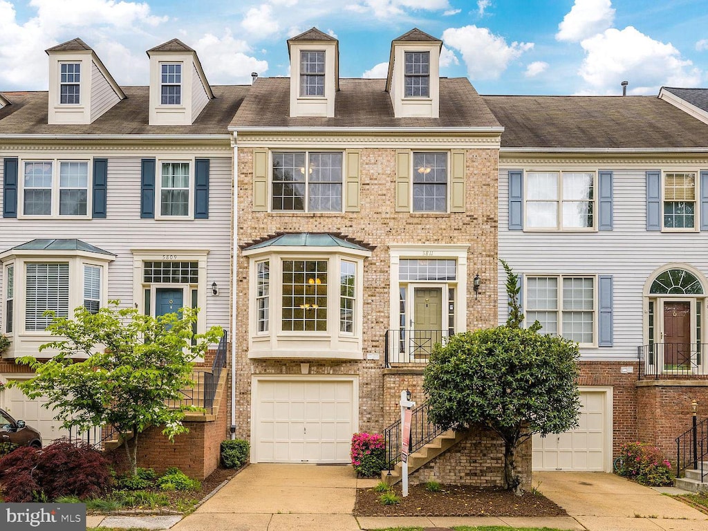 townhome / multi-family property featuring brick siding, stairway, an attached garage, and concrete driveway