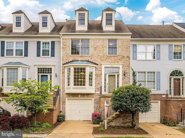 townhome / multi-family property featuring brick siding, stairway, an attached garage, and concrete driveway