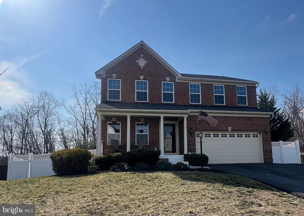 view of front of home featuring aphalt driveway, a garage, fence, and brick siding