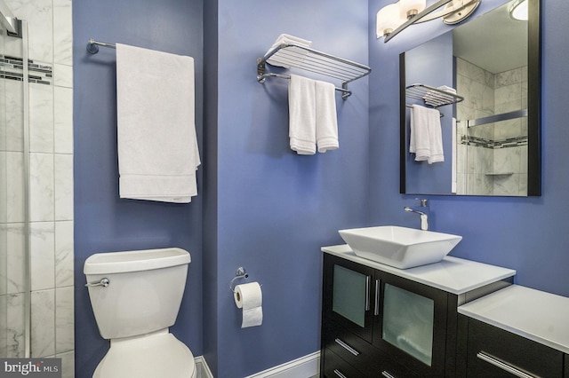 full bath featuring baseboards, tiled shower, toilet, and vanity