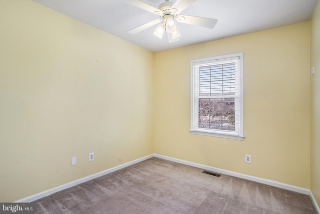 carpeted spare room with visible vents, ceiling fan, and baseboards