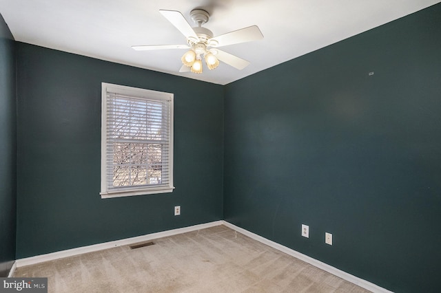 carpeted spare room with visible vents, baseboards, and a ceiling fan