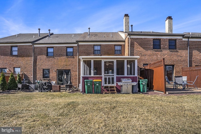 rear view of house with a yard, brick siding, a patio area, and a sunroom