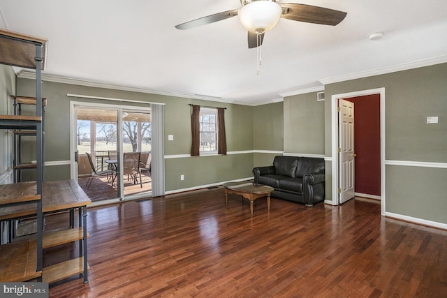 living area featuring wood finished floors, visible vents, baseboards, ceiling fan, and crown molding