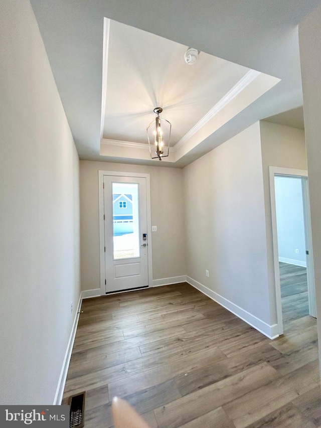 entrance foyer featuring a tray ceiling, wood finished floors, crown molding, baseboards, and a chandelier