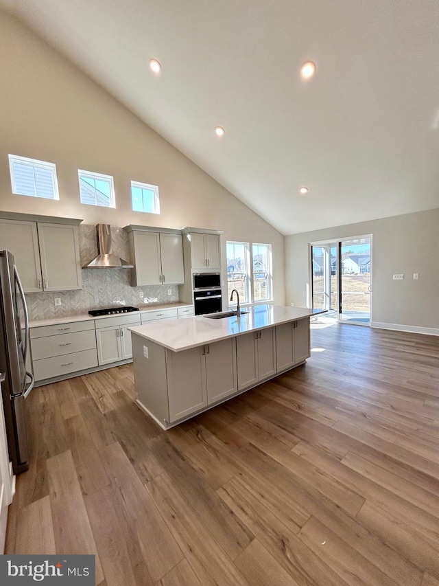 kitchen featuring visible vents, a sink, wood finished floors, appliances with stainless steel finishes, and wall chimney exhaust hood