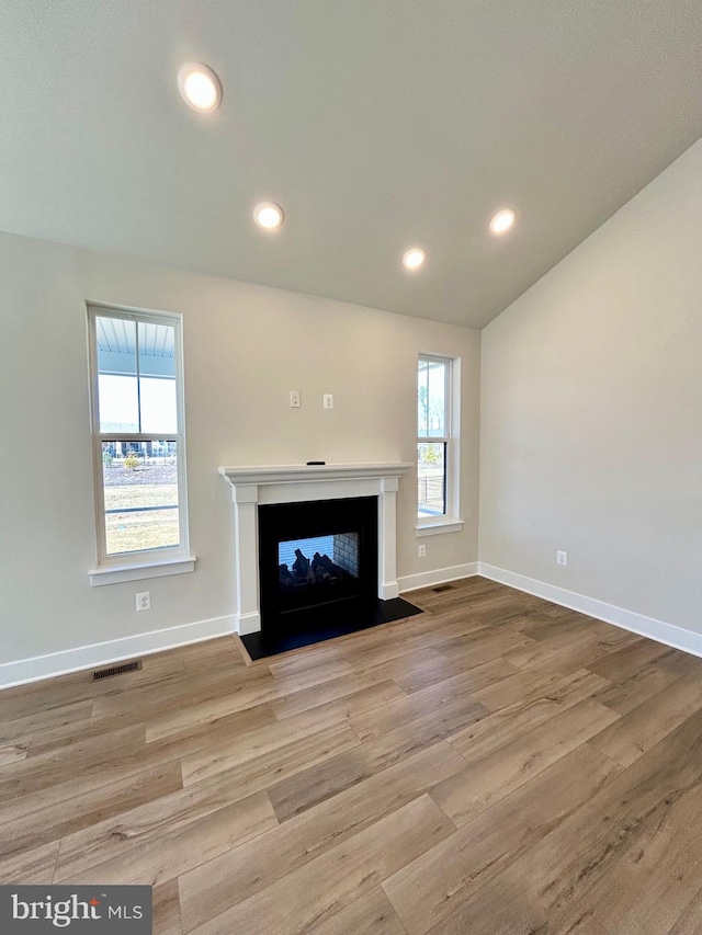 unfurnished living room with recessed lighting, a fireplace with flush hearth, wood finished floors, and visible vents