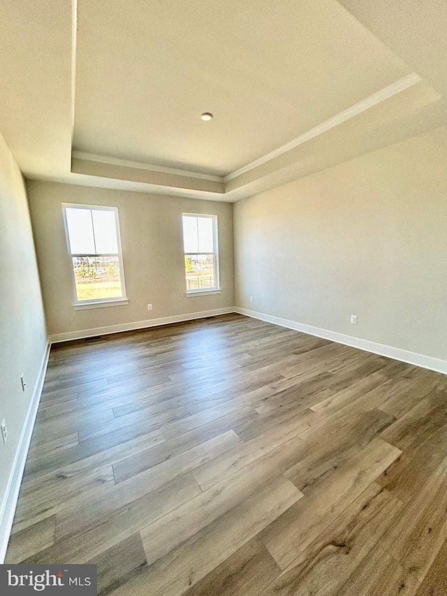 empty room with a raised ceiling, dark wood-style floors, and baseboards