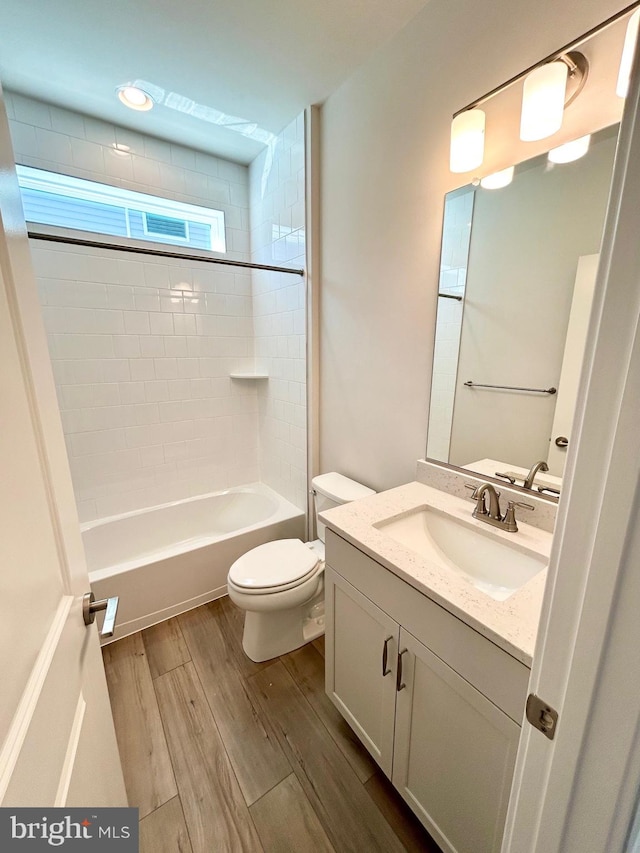 bathroom with vanity, toilet, wood finished floors, and shower / washtub combination