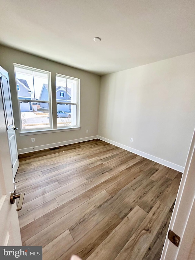 spare room featuring visible vents, baseboards, and wood finished floors