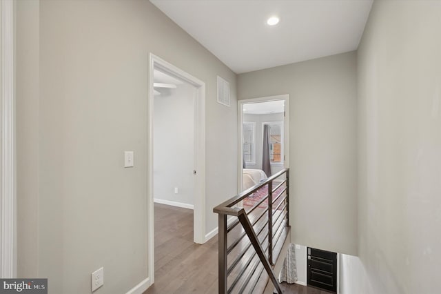 corridor featuring visible vents, an upstairs landing, wood finished floors, recessed lighting, and baseboards