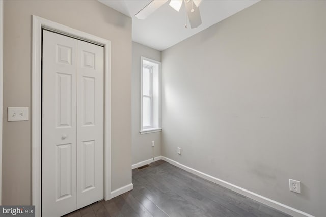 unfurnished bedroom featuring visible vents, ceiling fan, baseboards, dark wood finished floors, and a closet