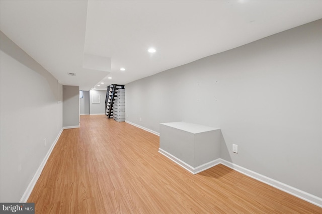 finished below grade area with light wood finished floors, recessed lighting, stairs, and baseboards