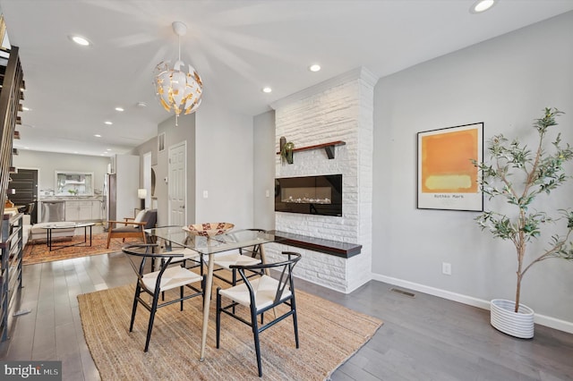 dining room featuring visible vents, dark wood finished floors, recessed lighting, a large fireplace, and baseboards