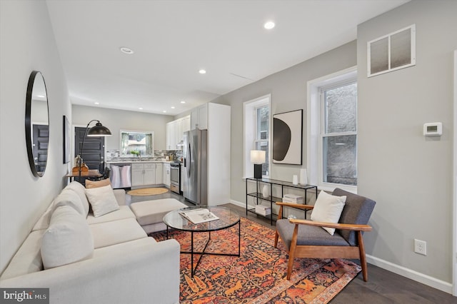 living area featuring recessed lighting, visible vents, baseboards, and wood finished floors