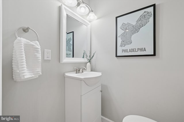 bathroom with baseboards, toilet, and vanity