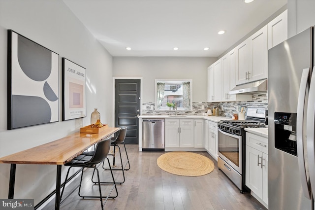 kitchen with stainless steel appliances, decorative backsplash, light countertops, white cabinets, and under cabinet range hood