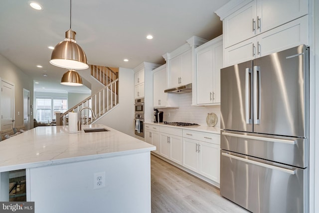 kitchen with a sink, stainless steel appliances, under cabinet range hood, and white cabinets