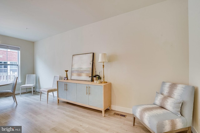 sitting room featuring visible vents, light wood-type flooring, and baseboards