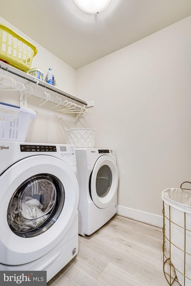 laundry room featuring light wood finished floors, baseboards, laundry area, and washer and clothes dryer