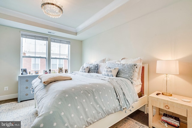 bedroom featuring a tray ceiling, baseboards, and visible vents