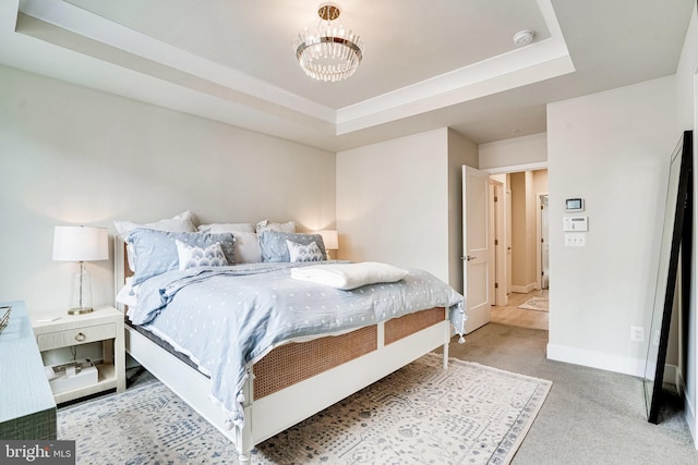 bedroom with a tray ceiling, baseboards, carpet, and a chandelier