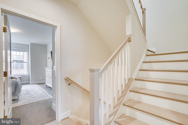 staircase featuring baseboards and carpet floors