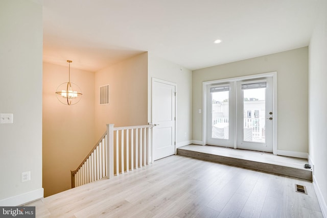 foyer entrance featuring visible vents, an inviting chandelier, baseboards, and wood finished floors